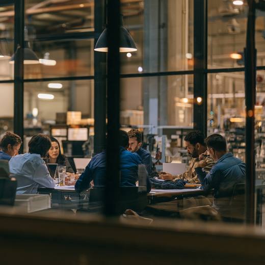 A team meeting in an office overlooking a warehouse floor