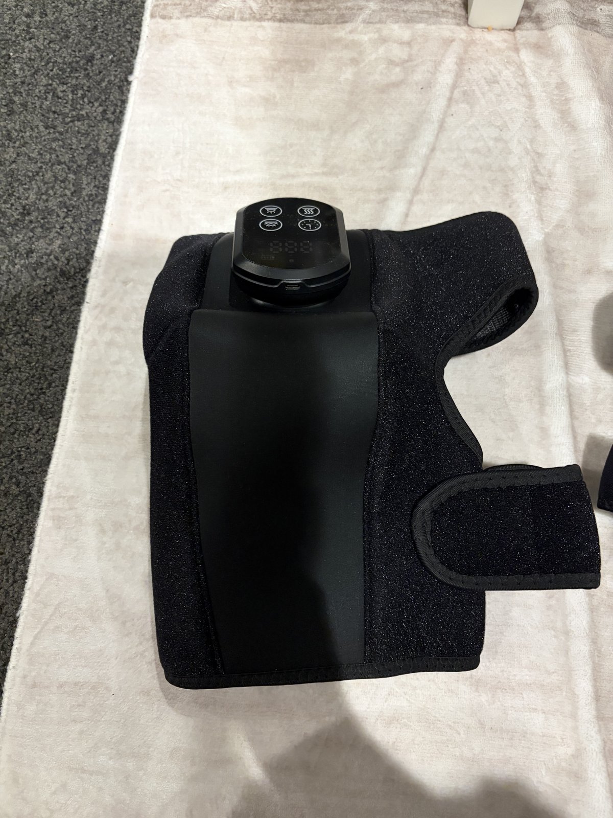 The knee brace laid flat showing the control unit and heat and light panel